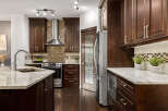 This spacious kitchen boasts dark wood cabinetry, granite countertops, and a sleek stainless steel range with a matching hood.