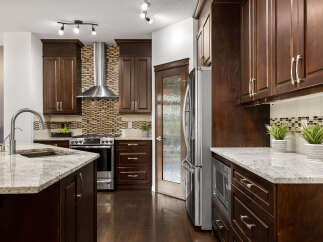 This spacious kitchen boasts dark wood cabinetry, granite countertops, and a sleek stainless steel range with a matching hood.