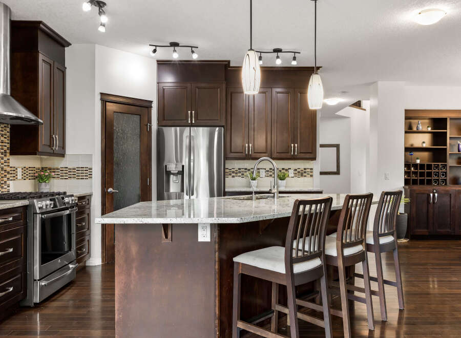 Experience luxury in this stunning kitchen featuring rich dark wood cabinetry and a spacious granite island perfect for entertaining.