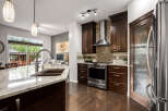 Experience luxury in this stunning kitchen featuring dark wood cabinetry, granite countertops, and a sleek stainless steel range with a mosaic tile backsplash.