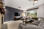 Experience modern living in this spacious living room, featuring a striking dark gray accent wall with a geometric design that perfectly complements the large flat-screen TV.