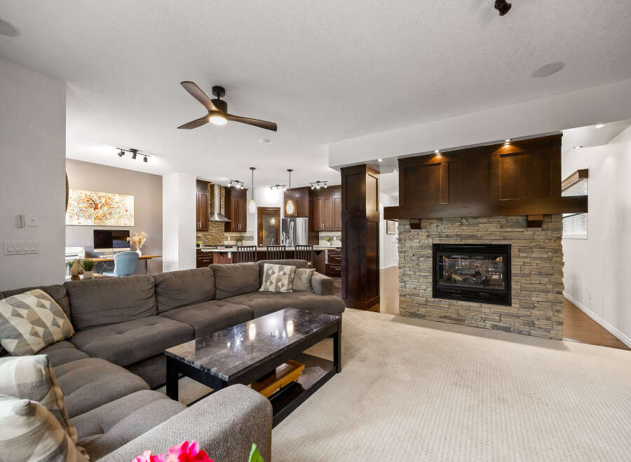 Experience luxury living in this stunning open-concept home, featuring a modern living room with a cozy stone fireplace and a spacious sectional sofa.