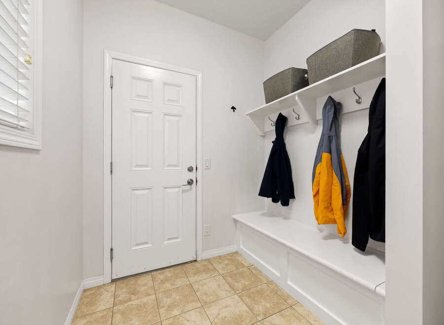 This entryway features a white door with a six-panel design, complemented by a built-in white bench with storage.