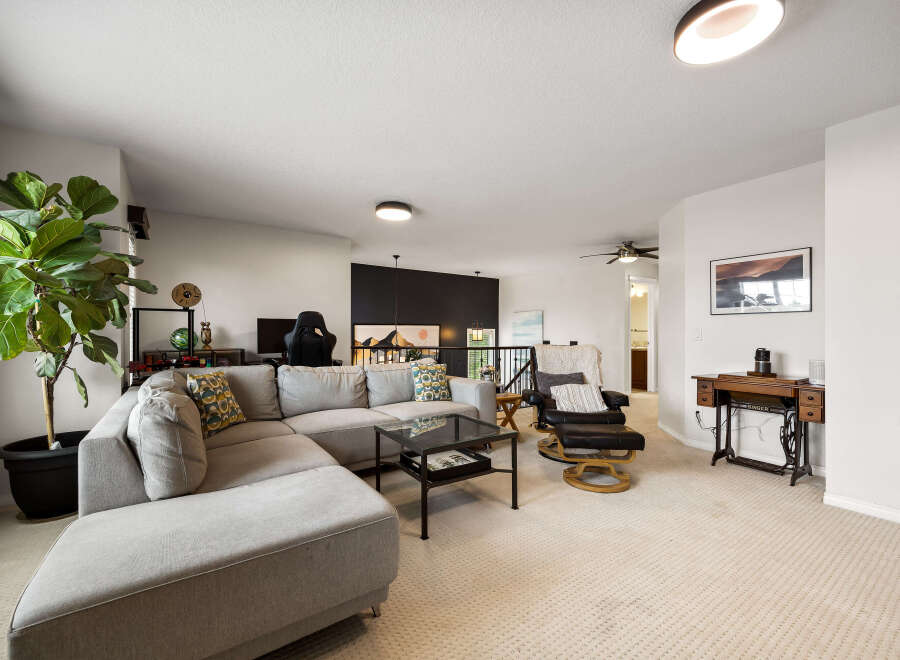 This spacious living room features a large sectional sofa, a comfortable recliner, and a stylish coffee table, perfect for relaxing or entertaining.