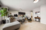 This spacious living room features a large sectional sofa, a comfortable recliner, and a stylish coffee table, perfect for relaxing or entertaining.