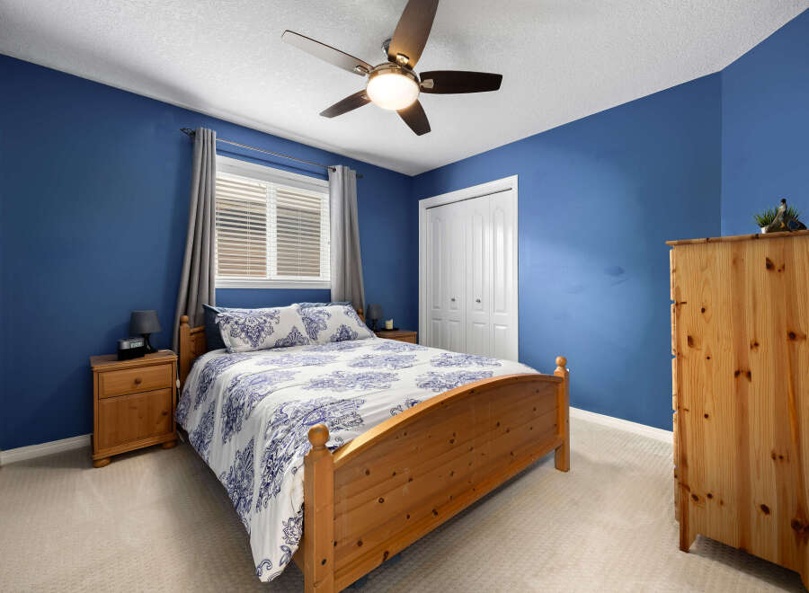 This cozy bedroom features a comfortable queen-size bed with a blue and white patterned comforter, complemented by a wooden headboard and matching nightstands.