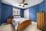 This cozy bedroom features a comfortable queen-size bed with a blue and white patterned comforter, complemented by a wooden headboard and matching nightstands.