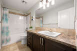 This bright and clean bathroom features a spacious white bathtub with a decorative shower curtain and a modern vanity with a white sink and ample counter space.