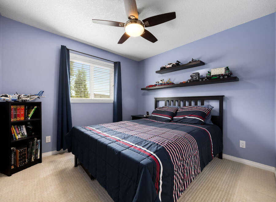 This charming bedroom features a comfortable queen-size bed with a navy blue comforter adorned with red and white stripes, complemented by matching pillows.