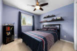This charming bedroom features a comfortable queen-size bed with a navy blue comforter adorned with red and white stripes, complemented by matching pillows.