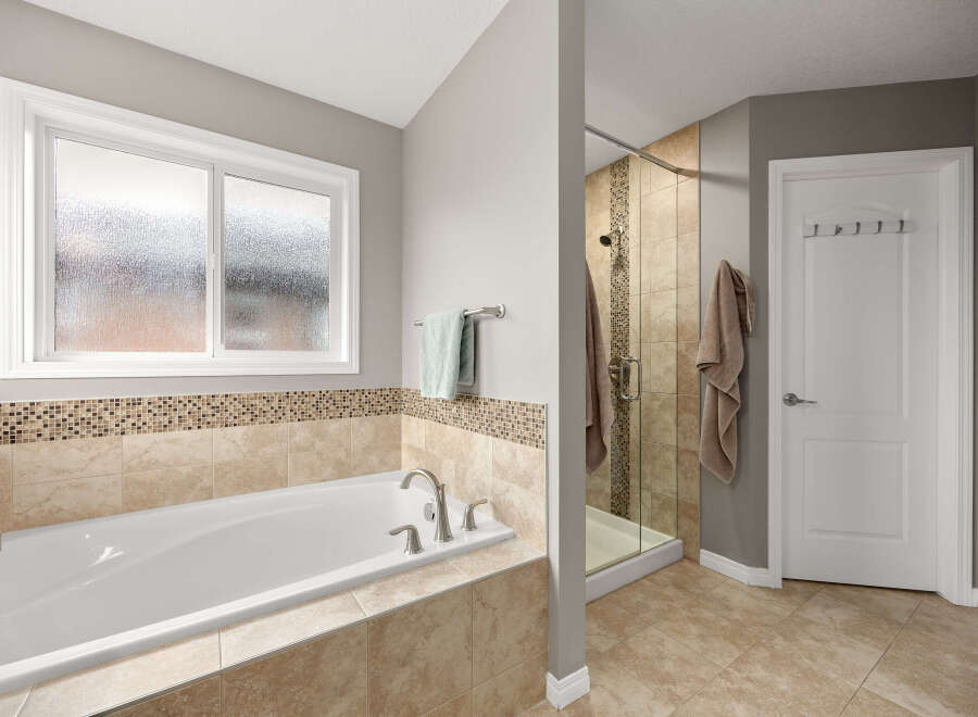 Indulge in relaxation in this luxurious bathroom featuring a deep soaking tub and a separate glass-enclosed shower with elegant tilework.