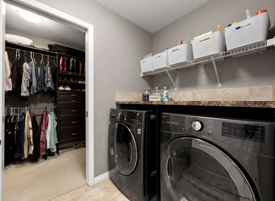 This spacious laundry room features a large walk-in closet with ample storage for clothing and shoes, including a dedicated section for boots.