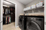 This spacious laundry room features a large walk-in closet with ample storage for clothing and shoes, including a dedicated section for boots.