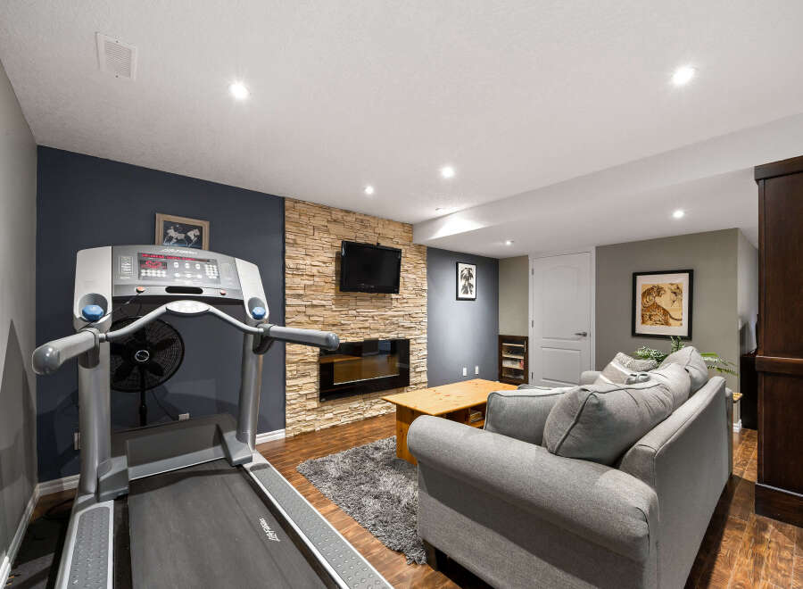This finished basement offers a versatile living space, perfect for both relaxation and fitness.