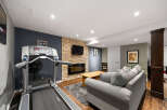 This finished basement offers a versatile living space, perfect for both relaxation and fitness.
