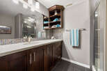 This modern bathroom features a sleek vanity with dark wood cabinetry and a white countertop, complemented by a mosaic tile backsplash.