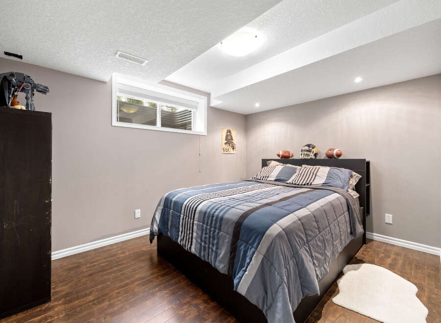 Discover this charming bedroom featuring a comfortable bed with a stylish striped comforter and coordinating pillows.