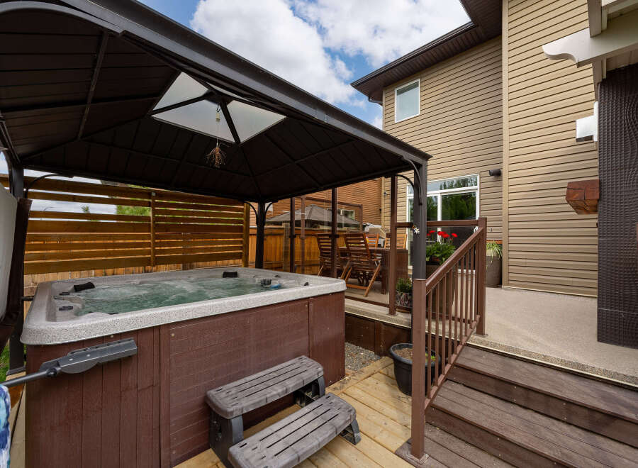 Experience ultimate relaxation in this backyard oasis, featuring a luxurious hot tub under a protective gazebo.