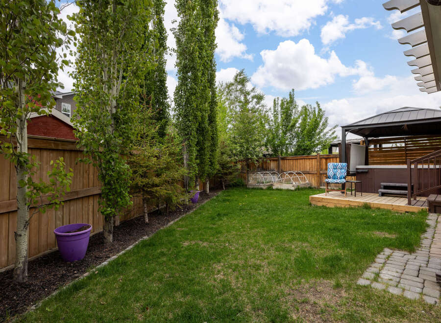 Enjoy outdoor living in this spacious backyard featuring a luxurious hot tub under a covered gazebo, perfect for relaxation.