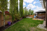 Enjoy outdoor living in this spacious backyard featuring a luxurious hot tub under a covered gazebo, perfect for relaxation.