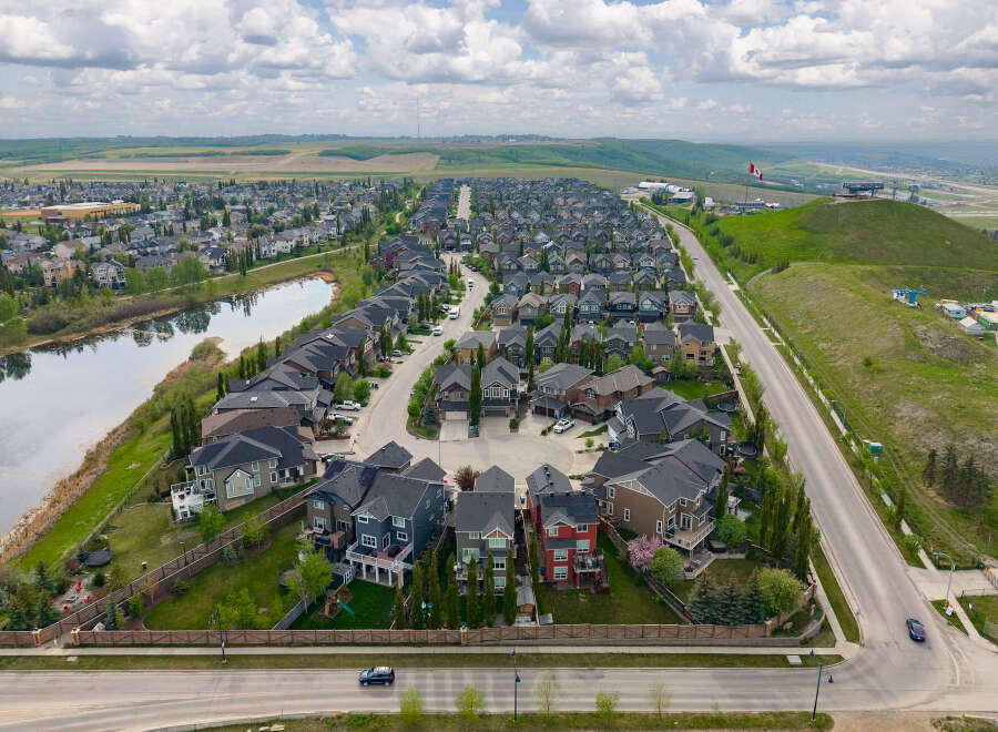 Discover this stunning suburban neighborhood featuring modern homes with diverse architectural styles, nestled alongside a serene pond and lush green spaces.