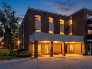 Experience comfortable living in this charming brick building, beautifully illuminated at dusk.