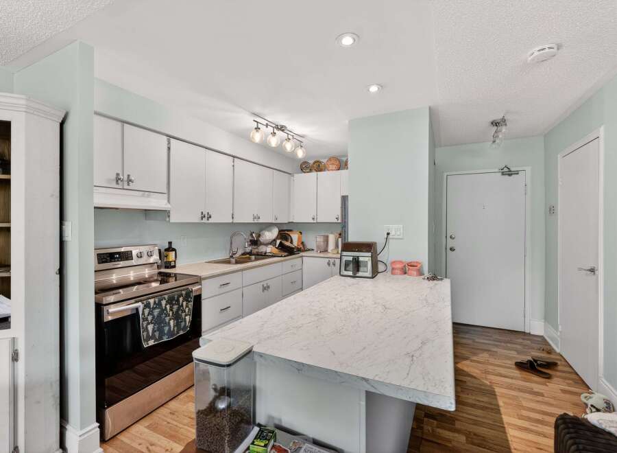 Discover this charming kitchen featuring sleek white cabinetry and a spacious marble-look island, perfect for meal prep and casual dining.
