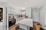 Discover this charming kitchen featuring sleek white cabinetry and a spacious marble-look island, perfect for meal prep and casual dining.