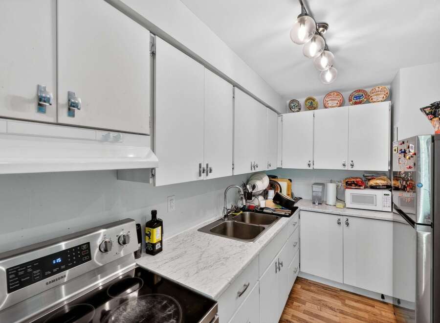 Discover this charming kitchen featuring sleek white cabinetry and a durable marble-patterned countertop.