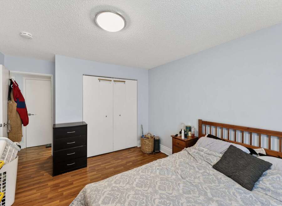 Discover comfort and convenience in this inviting bedroom, featuring a spacious bed with a patterned comforter and a dark grey accent pillow.