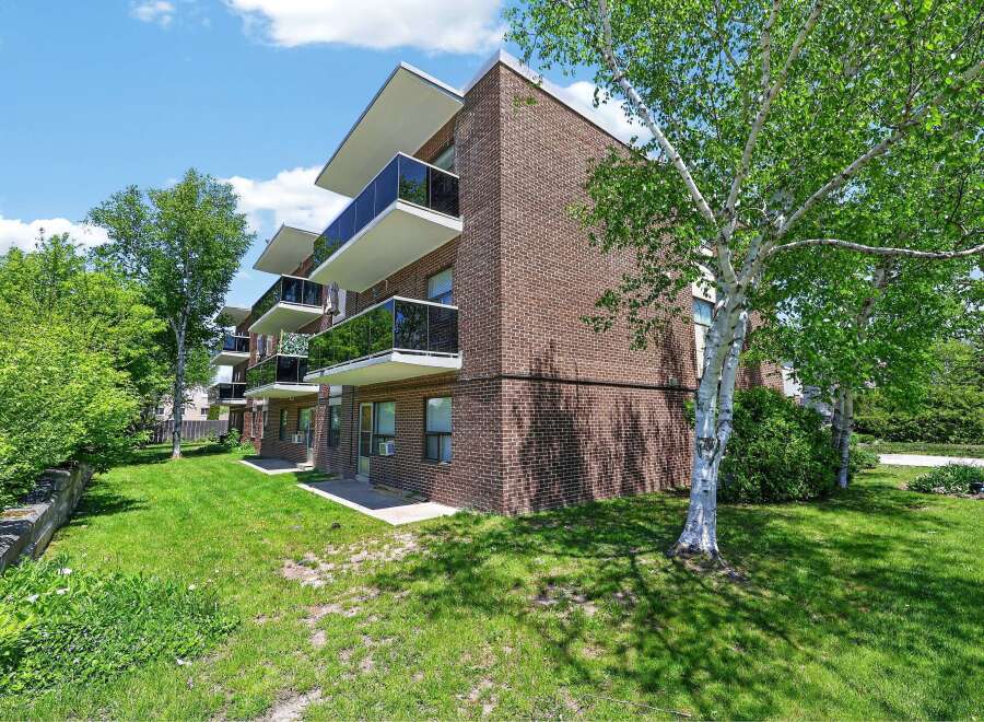 Discover modern living in this charming brick apartment building, featuring sleek balconies with glass railings perfect for enjoying the outdoors.