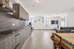 Experience modern living in this beautifully appointed apartment, featuring a sleek, integrated kitchen with ample cabinet space and a stylish backsplash.