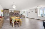 Experience coastal living in this spacious open-plan apartment featuring a modern kitchen and a dining area perfect for gatherings.