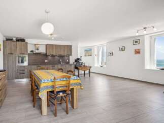 Experience coastal living in this spacious open-plan apartment featuring a modern kitchen and a dining area perfect for gatherings.