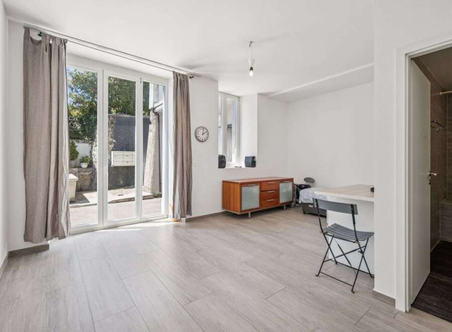 This bright studio apartment features a spacious living area with large glass doors leading to an outdoor space.