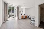 This bright studio apartment features a spacious living area with large glass doors leading to an outdoor space.