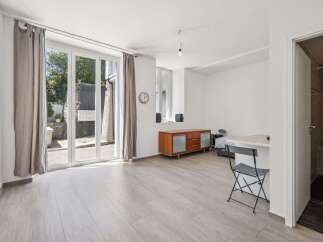 This bright studio apartment features a spacious living area with large glass doors leading to an outdoor space.