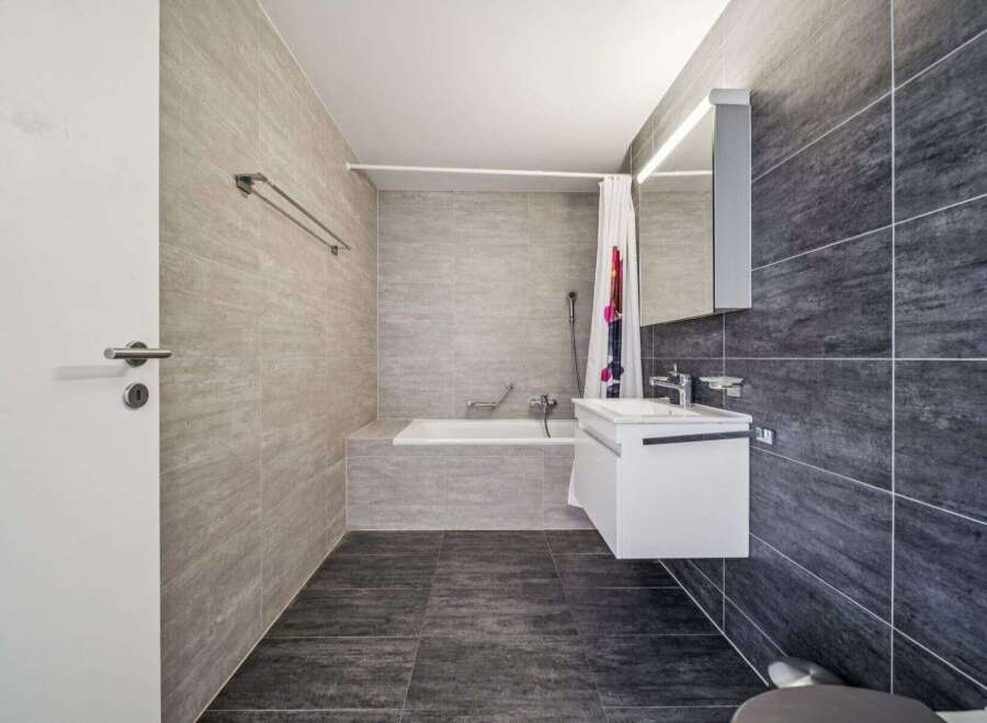 Experience modern comfort in this stylish bathroom featuring a sleek white vanity and a deep soaking tub, perfect for unwinding.