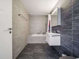Experience modern comfort in this stylish bathroom featuring a sleek white vanity and a deep soaking tub, perfect for unwinding.