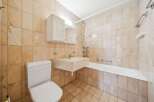 This bathroom features a classic design with beige marble tiles adorning the walls and floor, creating a warm and inviting atmosphere.