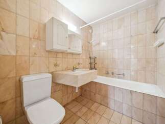 This bathroom features a classic design with beige marble tiles adorning the walls and floor, creating a warm and inviting atmosphere.