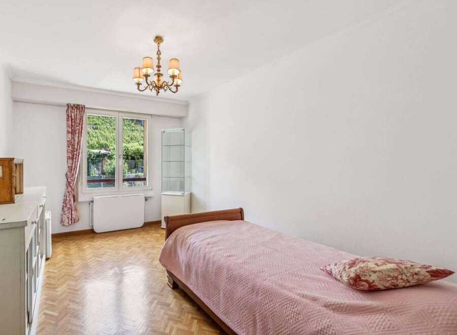 Discover this charming bedroom featuring a comfortable single bed adorned with a pink textured blanket and a decorative pillow.