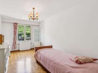 Discover this charming bedroom featuring a comfortable single bed adorned with a pink textured blanket and a decorative pillow.