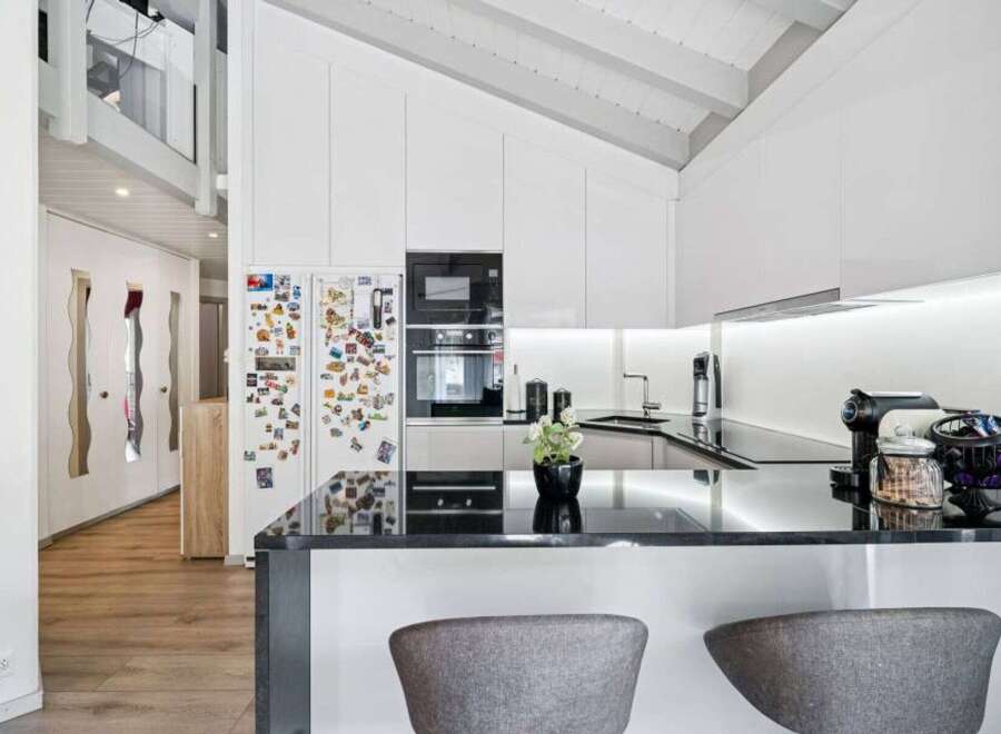 Experience modern living in this stunning kitchen featuring sleek white cabinetry and a sophisticated black granite countertop.