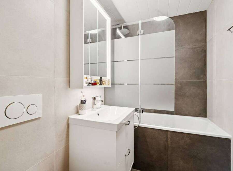 This modern bathroom features a sleek white vanity with a vessel sink and a wall-mounted medicine cabinet.