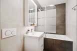 This modern bathroom features a sleek white vanity with a vessel sink and a wall-mounted medicine cabinet.