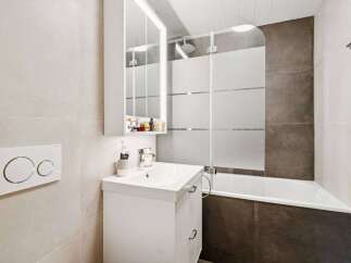 This modern bathroom features a sleek white vanity with a vessel sink and a wall-mounted medicine cabinet.