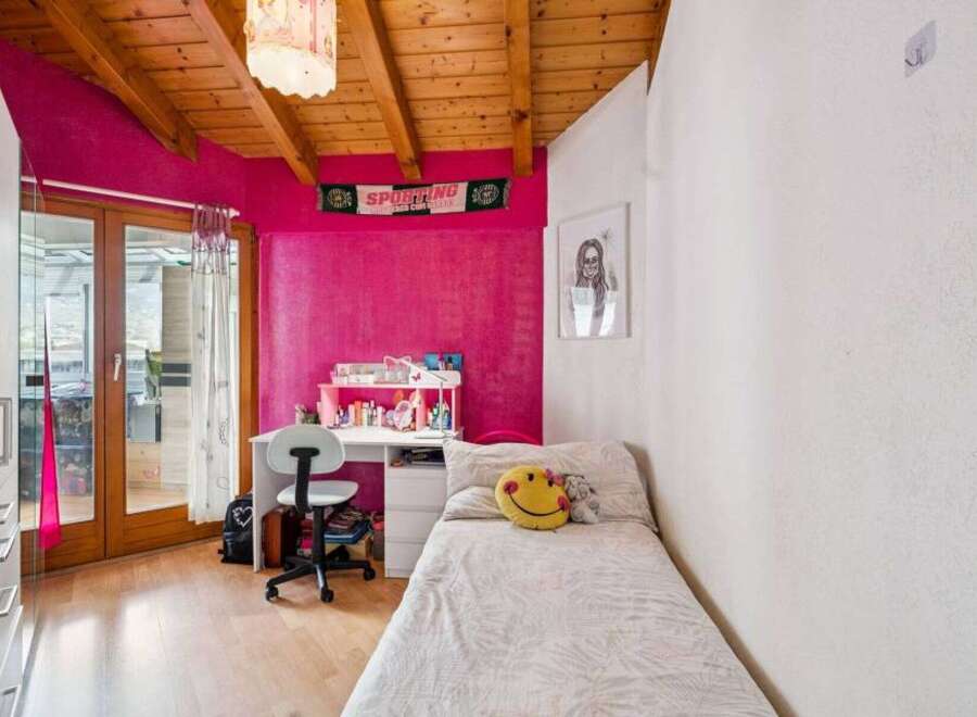 Bright and cheerful bedroom featuring a vibrant pink accent wall and a cozy single bed adorned with a smiley face pillow.