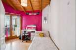Bright and cheerful bedroom featuring a vibrant pink accent wall and a cozy single bed adorned with a smiley face pillow.