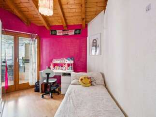 Bright and cheerful bedroom featuring a vibrant pink accent wall and a cozy single bed adorned with a smiley face pillow.
